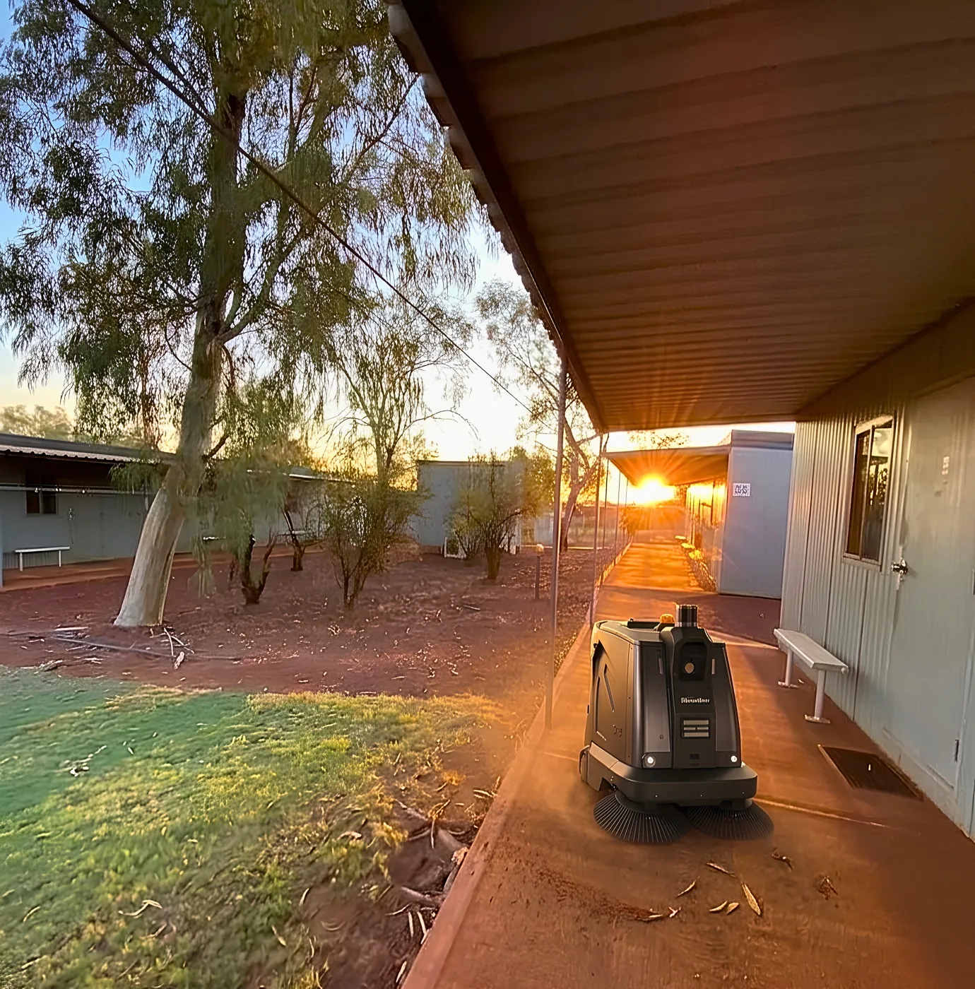 Perth Robots S5 autonomous sweeper cleaning a path between accommodation dongas at a WA mining camp at sunset
